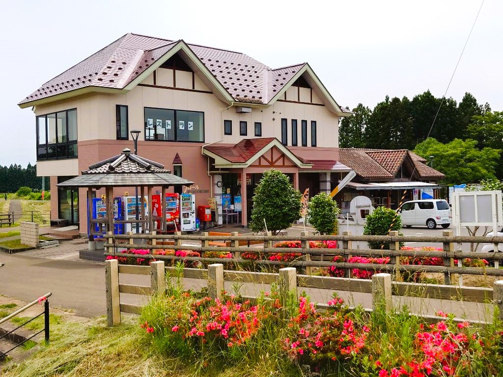 朱色の屋根で外壁がベージュ色をした2階建ての道の駅「みずさわ」の建物外観を駐車場側から撮影した写真