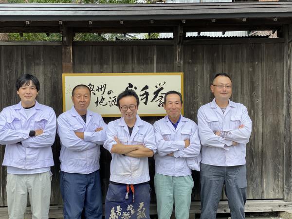 「奥州の地酒 岩手誉」と書かれた看板前で腕組みをして笑顔で写っている5名の男性の写真
