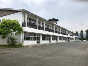 白い外壁で2階建ての前沢中学校の校舎の横に木が植えられている写真