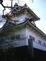 白い外壁の青葉城の一角を咲き始めの桜と共に写した写真