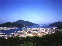 海や山、工場などが複雑に入り組んだリアス式海岸となっている、晴れた日の宇和島湾を高台から撮影した写真