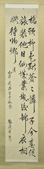 金色の台紙の縦長の掛軸で、墨で漢詩が書かれている新平筆漢詩の写真