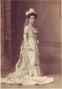 裾の長い白いドレスを身につけ、日本髪にウェディングベールをつけて立っている和子夫人の全身を写したモノクロ写真