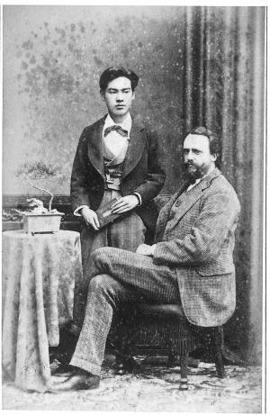 椅子に座っているローレッツと、ローレッツのすぐそばに立っている新平が写っている白黒写真