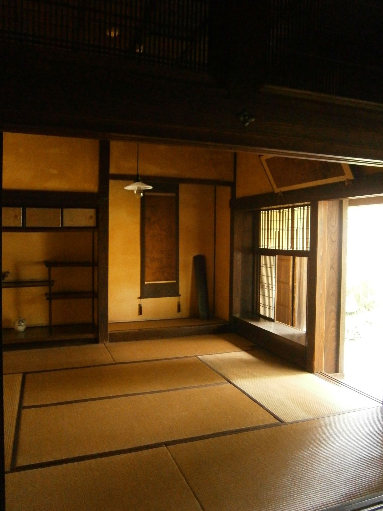 床の間に掛け軸があり、右側の窓が開けられ太陽光が入ってきている上座敷の部屋の写真