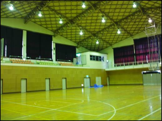 天井の照明が点灯し広々としたバスケットボールコートが明るく照らされている写真
