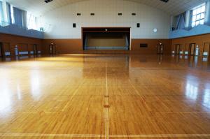 バスケットボールコート2面分の広さで正面奥にステージがある江刺西体育館内の写真