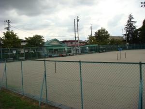 クラブハウスに隣接し、周囲を緑色のフェンスで囲んだ水沢公園テニスコートの写真