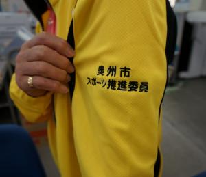 黄色いスポーツウエアーの左腕の部分に「奥州市スポーツ推進委員」の刺繍がはいっている写真