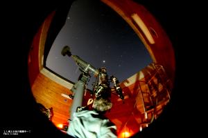 男性が大きな天体望遠鏡で星空を観察している様子の写真