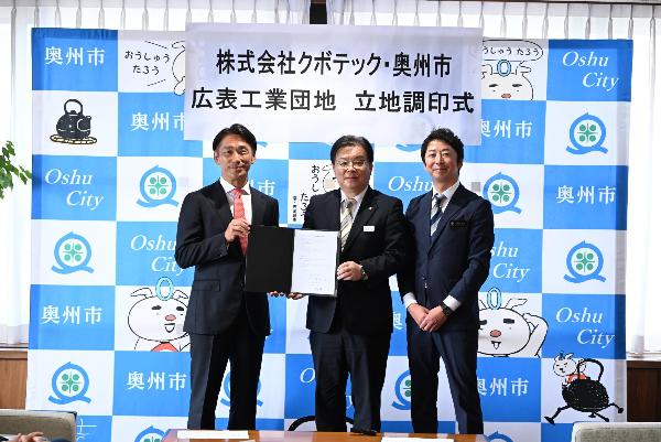 スーツの男性3人が並んで写真を撮っている様子