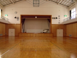 前方に舞台があり、天井にバスケットゴールが格納されている体育館の写真