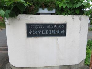 「国立天文台水沢VLBI観測所」と書かれたプレートがはめ込まれている白い門柱の写真