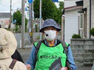 帽子を被り、マイクを付けた担当会員の佐々木さんが話をしている様子を正面から写した写真