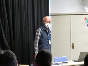 マスクを着けた亀谷館長が立って話をしている写真