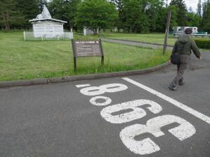 白字で39°8'と北緯が書かれている地面を写した写真