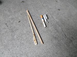 焼き鳥の串、割り箸、たばこの吸い殻が並べて置かれている集められたゴミの写真