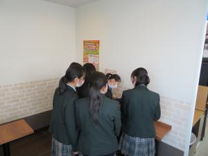 5名ほどの制服姿の女子生徒たちが、部屋の隅に設置された机の上で作業をしている写真