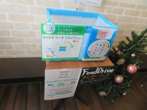 飾り付けされたツリーが設置されている壁際の一角にファミマフードドライブを紹介するポップや箱が用意されている写真