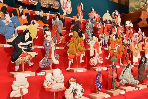 ひな壇に押し絵で作られた雛人形が様々な衣装やポーズをとって並べられている写真