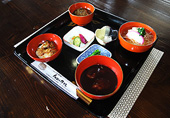 黒いお膳にお汁粉など4種類のお餅料理が入った朱色のお椀と、漬物などがのったお餅膳の写真