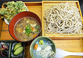 四角い木のお盆に、もりそば、薬味、野菜の天ぷら、なんばん餅、漬物がのったもりそばセットの写真