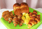 緑色のクロスの上に、クロワッサンや食パンが並べられている様子の写真