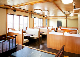 明るい和風の店内に、板張りの座敷席と複数のボックス席が並んでいる「牛肉料理 味心」の写真