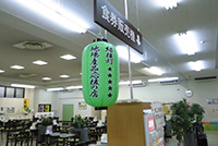 天井から「食券販売機」の看板と、緑色の提灯が下がった、飲食スペース前の食券売り場の写真