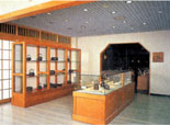 和風の室内に、鉄瓶などの南部鉄器が木製の棚や、展示ケースに並べられ展示してある写真