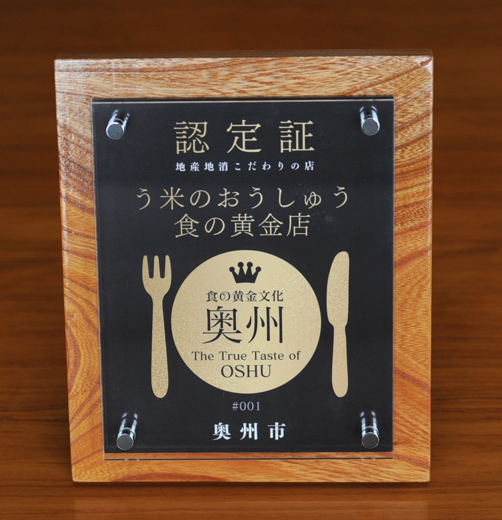 金色のスプーンとフォークのイラストの真ん中に食の黄金文化奥州と書かれた「う米(まい)のおうしゅう食の黄金店」認定書の写真