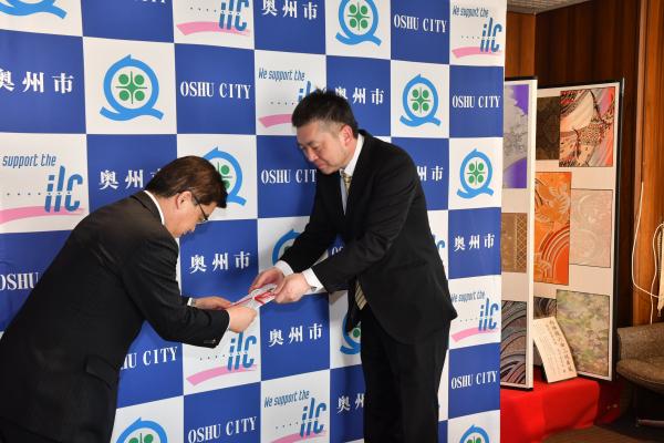 高橋執行役員工場長から目録を受け取っている倉成市長を写した寄贈式の様子の写真