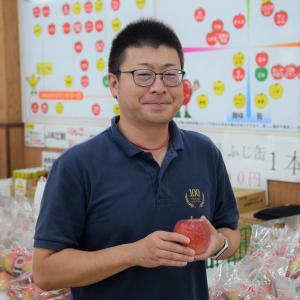 手にりんごを持ち、ネイビーのポロシャツを着ている岩手江刺農業協同組合（JA江刺） 及川さんの写真