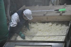全体の温度を均一にするために麹米を混ぜる作業を行っている作業者の写真