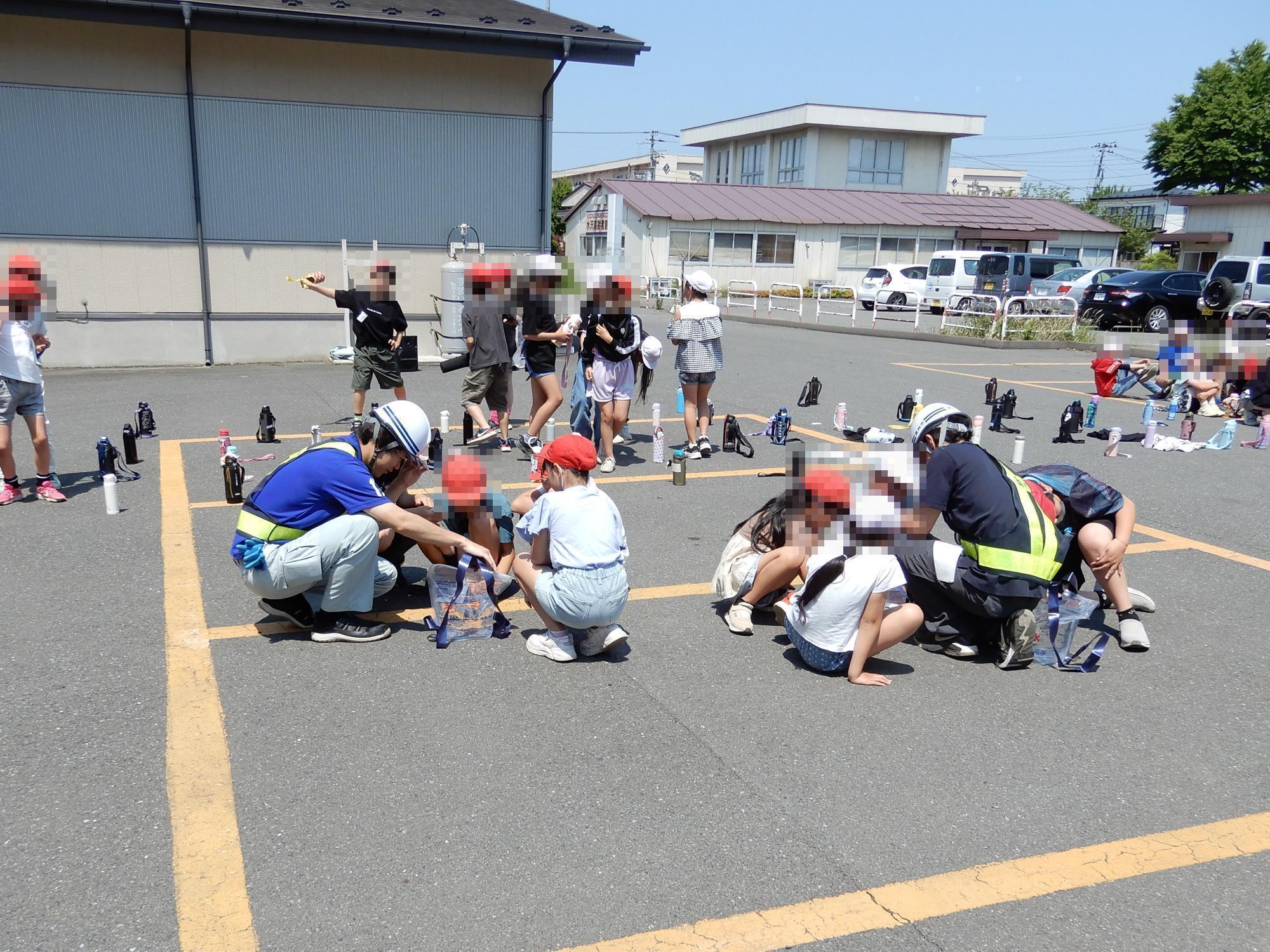 水を汲んだ給水袋に背負うための紐の取付方法を聞く参加者の様子の写真