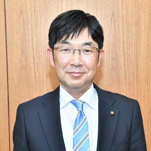 スーツ姿で眼鏡をかけた菅原 由和市議会議長を正面から撮影した写真