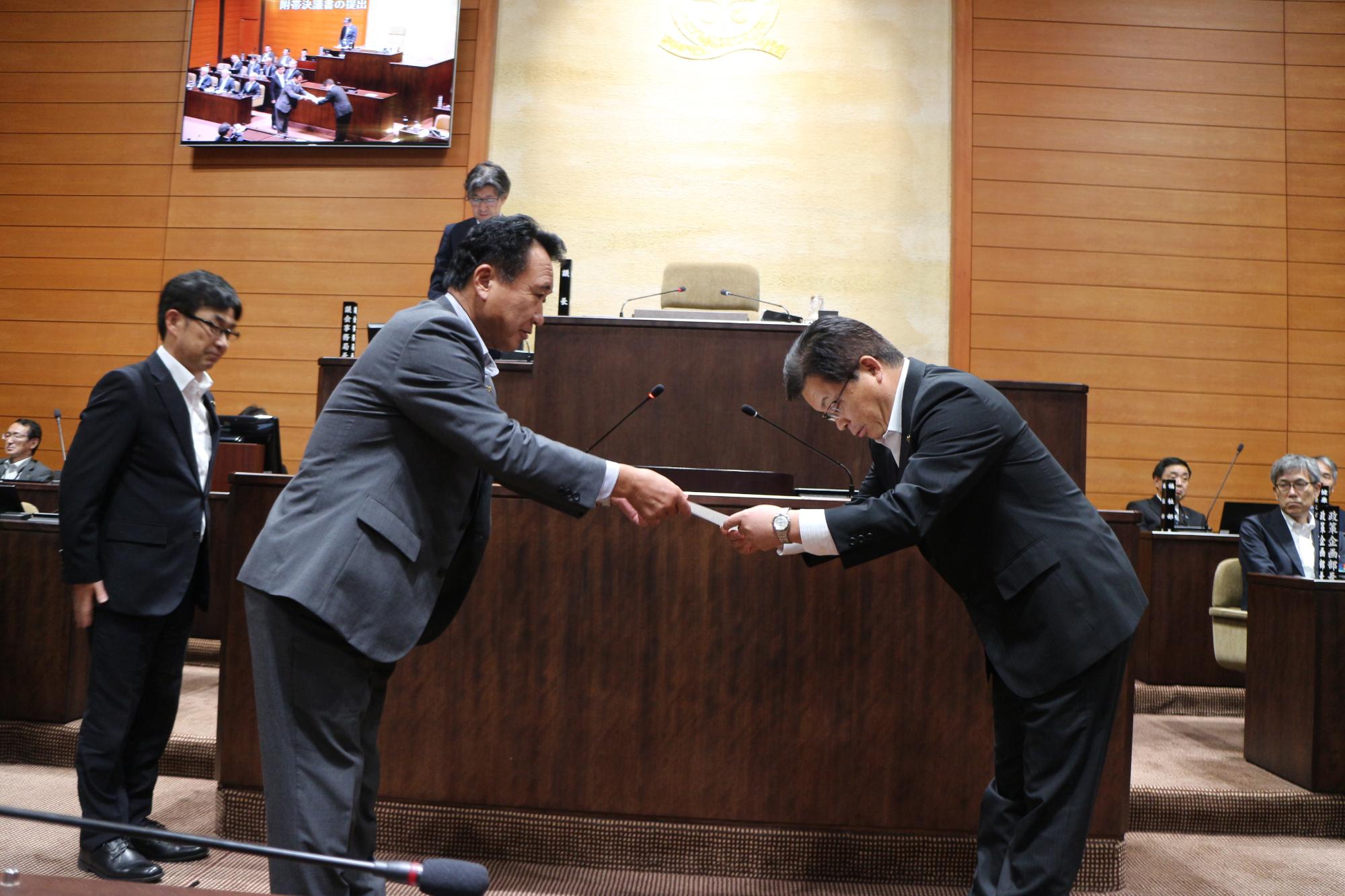 中西秀俊決算審査特別委員会委員長が市長へ政策提言決議文書を手渡す様子