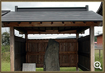 三方に囲いがされた左奥に案内板、中央に石碑が立つ豊田城跡碑の写真