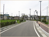 右側に歩道が作られ、前方は緩やかな左カーブになっている綺麗に舗装された道路を写した写真
