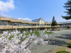 三角の形が山のように連なっている屋根が特徴的な校舎と写真手前に桜の花がアクセントで写っている南都田小学校の外観を写した写真
